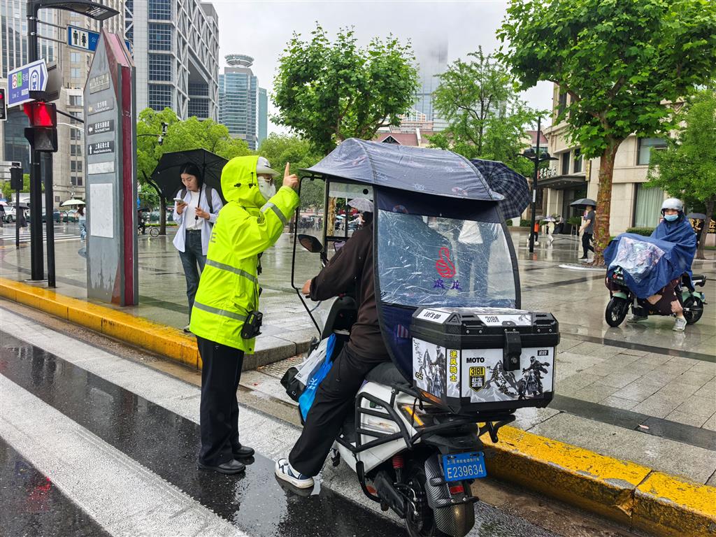 图为浦东公安分局交警支队一大队东方明珠女警中队民警正劝阻电动自行车驾驶员拆除雨棚(浦东警方供图,下同)